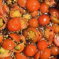 Gehalveerde cherrytomaten die sudderen in een donkere, stroperige saus.